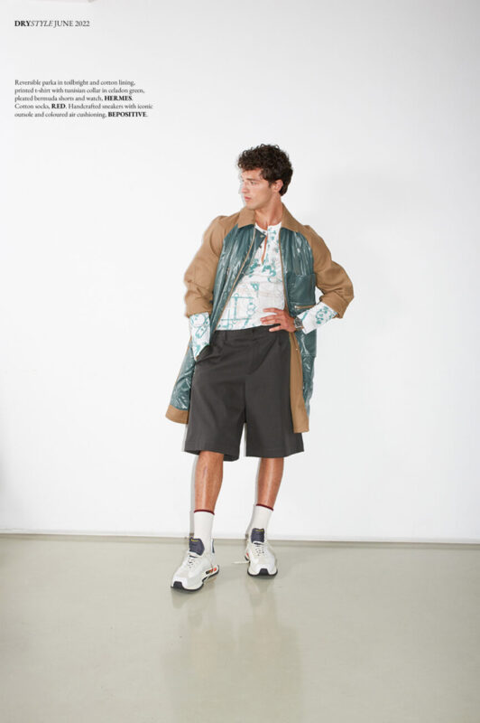 Reversible parka in toilbright and cotton lining, printed t-shirt with tunisian collar in celadon green, pleated bermuda shorts and watch, HERMES. Cotton socks, RED. Handcrafted sneakers with iconic outsole and coloured air cushioning, BE POSITIVE.